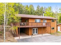 Two-story home features wood siding, a brown roof, and an expansive deck perfect for outdoor living at 11457 Nancys Dr, Conifer, CO 80433