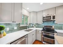 Updated kitchen with white countertops, stainless appliances, and green tiled backsplash at 11457 Nancys Dr, Conifer, CO 80433