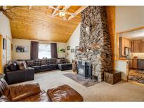 Inviting living room with a stone fireplace, wood ceiling and leather furniture at 31948 Highway 72, Golden, CO 80403