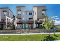 Modern townhome exterior featuring gray siding, balconies, green doors, and well-maintained front yards with wooden fences at 5654 N Emporia St, Denver, CO 80238