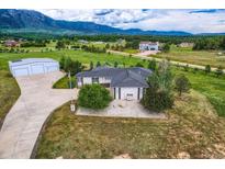 Stunning aerial view of a home with a large garage, and mountain views with rolling hills and scattered homes in the background at 16710 Vincent Ave, Monument, CO 80132