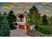 Charming home features a covered porch and two-car garage, surrounded by mature trees and lush landscaping at 386 Monte Vista Rd, Golden, CO 80401