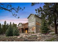 Inviting multi-story home with a stone base, complemented by a spacious wooden deck and mature trees at 1055 Divide View Dr, Golden, CO 80403