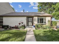 Charming brick home with well-manicured lawn, colorful flower beds, and inviting walkway at 4231 W Ponds Cir, Littleton, CO 80123