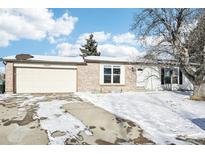 Brick ranch home with attached two-car garage and snowy front yard at 10975 Birch Dr, Thornton, CO 80233