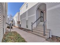 Inviting condo exterior with gray siding, concrete stairs, and an arched entryway at 11115 E Alameda Ave # 203, Aurora, CO 80012