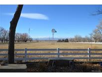 Scenic property view features an expansive field, a white fence, and a vintage windmill against a clear, blue sky at 7250 County Road 5, Erie, CO 80516