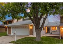 Charming home featuring attached two-car garage, brick accents, and a well-maintained front yard with mature tree at 7483 W Cedar Cir, Lakewood, CO 80226