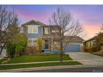 Charming two-story home featuring a blend of blue siding and stone accents with a well-manicured lawn at 15767 E 109Th Ave, Commerce City, CO 80022