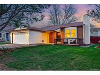 Charming home featuring a well-manicured lawn, front porch, and attached two-car garage at 12432 Bellaire St, Thornton, CO 80241