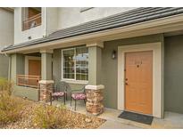Charming condo front porch featuring seating area, number 104, and beautiful stone column accents at 22675 E Ontario Dr # 104, Aurora, CO 80016