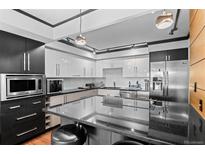 Modern kitchen featuring stainless steel appliances, black granite countertops, and sleek white cabinetry at 1551 Larimer St # 1106, Denver, CO 80202