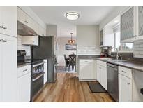 Bright kitchen with stainless steel appliances, white cabinets, and wood-look flooring at 8746 Sunridge Hollow Rd, Parker, CO 80134