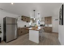 Updated kitchen with island, stainless steel appliances, and wood cabinets at 1131 S Raleigh St, Denver, CO 80219