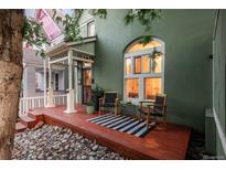 Inviting front porch with seating, striking arched window, and a charming, colorful exterior at 616 W 1St Ave, Denver, CO 80223