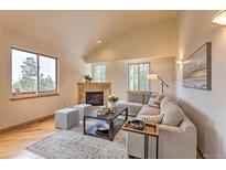 Bright living room featuring a stone fireplace, vaulted ceilings, and lots of natural light from large windows at 100 Apache Rd, Evergreen, CO 80439