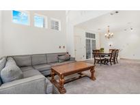 Spacious living room with soaring ceilings, multiple windows, and adjacent dining area at 9530 E Florida Ave # 2001, Denver, CO 80247