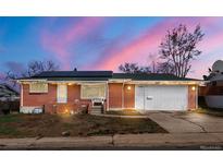 Charming single-story brick home featuring a two-car garage, solar panels, and cozy front porch, and nice landscaping at 8140 Pennsylvania Way, Denver, CO 80229