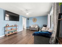 Inviting living room featuring a ceiling fan, hardwood floors, and large windows for ample natural light at 8140 Pennsylvania Way, Denver, CO 80229
