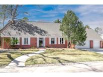 Charming brick home featuring white shutters, a well-manicured lawn, and mature trees under a bright blue sky at 995 S Jackson St, Denver, CO 80209