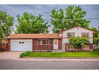 Charming two-story home with brick and white siding, a well-maintained lawn, and an attached two car garage at 1583 Skeel St, Brighton, CO 80601