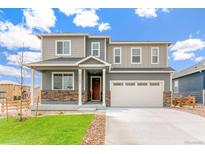 Charming two-story home featuring stone accents, a well-manicured lawn, and a convenient two-car garage at 2206 Crosswind St, Fort Lupton, CO 80621