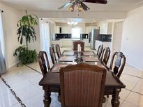 A dining room with hardwood table and chairs, with kitchen in background, illuminated by hanging chandelier at 21561 E 48Th Pl, Denver, CO 80249