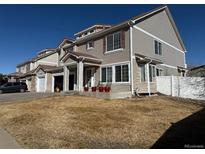 Charming two-story home featuring a covered porch, red potted plants, and a well-manicured lawn at 21561 E 48Th Pl, Denver, CO 80249