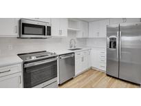 Modern kitchen boasts stainless steel appliances, white cabinets, and sleek countertops at 14001 E Marina Dr # 603, Aurora, CO 80014