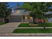 Charming two-story home featuring a well-maintained lawn, a covered front porch, and an attached two-car garage at 5229 Nighthawk Pkwy, Brighton, CO 80601
