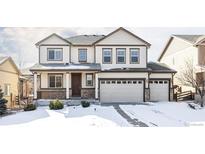 Charming two-story home with a three-car garage and snow-covered front yard at 21572 E Union Dr, Aurora, CO 80015