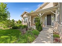Charming front porch with stone accents and a well-manicured lawn and garden at 4932 Democrat Dr, Broomfield, CO 80023