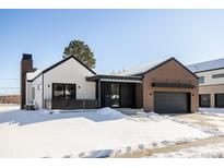 Stunning modern farmhouse exterior with brick and white siding, snowy landscape at 3120 Braun Ct, Golden, CO 80401