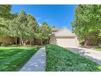 Charming home featuring mature trees, a well-manicured lawn, and a welcoming two-car garage at 6731 S Kearney Ct, Centennial, CO 80112