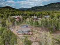 Stunning aerial view of a mountain home surrounded by lush forest and mature trees with a wooden fence surrounding the property at 9288 Krashin Dr, Conifer, CO 80433