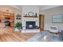 Inviting living room features a cozy fireplace, wood floors, and an open layout to the kitchen at 9288 Krashin Dr, Conifer, CO 80433