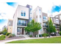 Stunning three-story townhome featuring modern architecture and a well-maintained front yard and small patio at 15878 E Broncos Pl, Englewood, CO 80112