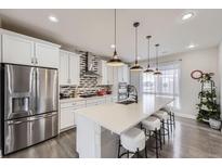 Modern kitchen featuring stainless steel appliances, white cabinetry and a large island with pendant lighting at 15878 E Broncos Pl, Englewood, CO 80112