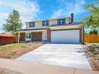 Charming two-story home featuring a brick facade, two-car garage, and a well-maintained front yard at 8694 E Eastman Ave, Denver, CO 80231