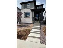 Two-story home featuring a mix of stone and gray siding and a welcoming front porch at 7360 Watercress Dr, Littleton, CO 80125