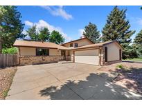 Charming home featuring brick accents, a two-car garage, and mature trees at 12408 E Ohio Ave, Aurora, CO 80012