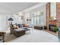 Bright living room features a brick fireplace, high ceilings, and a comfortable gray sectional sofa at 4231 S Fairplay Cir # E, Aurora, CO 80014