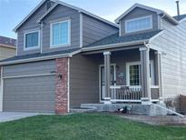 Charming two-story home with a covered front porch, brick accents, and an attached garage at 21851 Omaha Ave, Parker, CO 80138