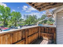 A wooden balcony overlooks a parking area and lush greenery, with a partial view of the sky above at 381 S Ames St # E104, Lakewood, CO 80226