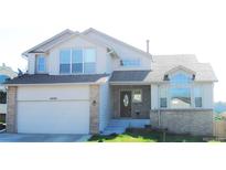 Charming two-story home featuring a two-car garage, brick accents, and manicured lawn, with a large front window at 6464 S Swadley Way, Littleton, CO 80127