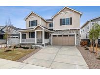 Charming two-story home featuring a covered porch, two-car garage and a combination of stone and siding exterior at 24788 E 40Th Ave, Aurora, CO 80019