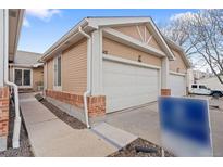 Inviting home exterior featuring a clean two-car garage and well-maintained tan siding with brick accents at 8112 Gray Ct # 394, Arvada, CO 80003