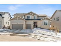 Charming two-story home with a three-car garage, stone accents, and a well-maintained lawn at 5411 Edenborn Way, Castle Rock, CO 80104