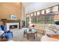 Bright living room featuring a fireplace, large windows, and a plush white sectional sofa at 9873 Greensview Cir, Lone Tree, CO 80124