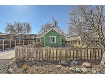Charming home exterior with a fenced yard, green siding and a red door at 6000 W 29Th Ave, Denver, CO 80214